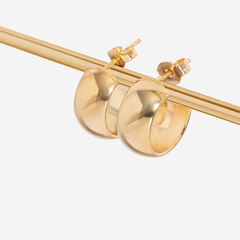 chunky gold hoop earring and a soft-focus background emphasizing the earring's shine