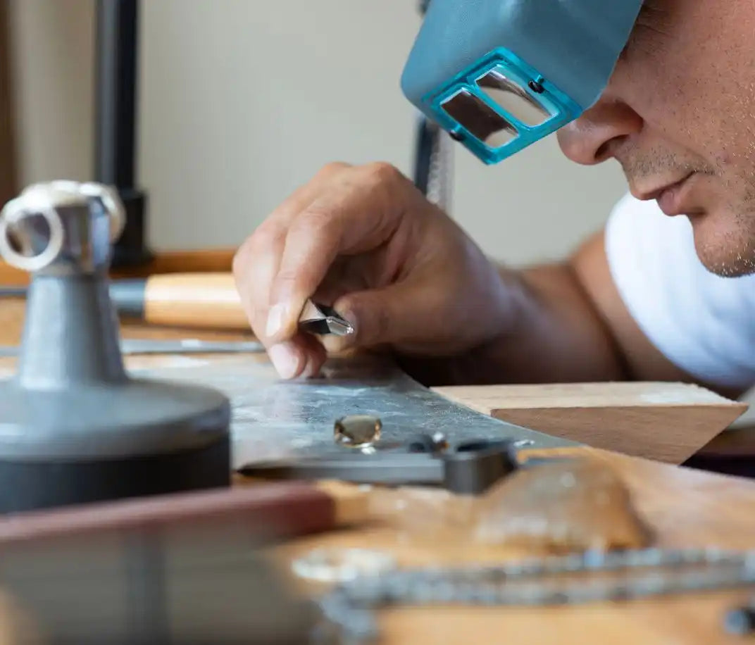 Someone using a magnifying device while working on what appears to be jewelry or small mechanical parts.