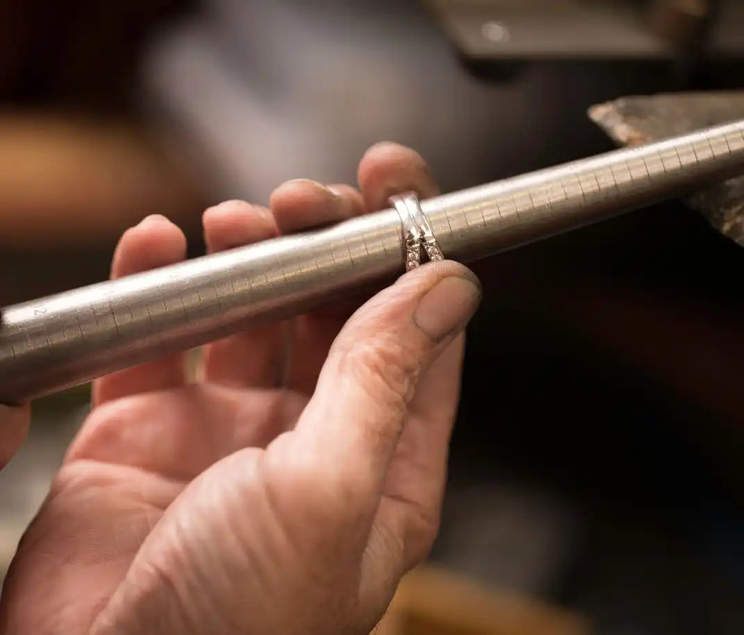 Diamond engagement ring being held against a metal rod.
