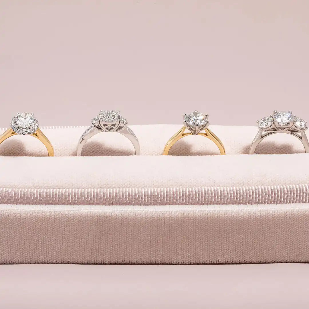 Four diamond engagement rings alternating between gold and silver bands.