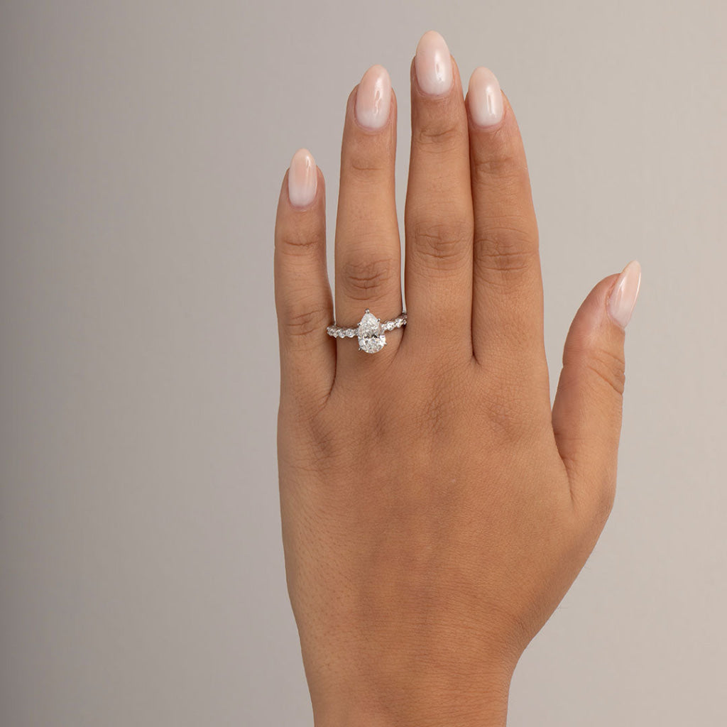 pear cut engagement ring with diamond band on models hand