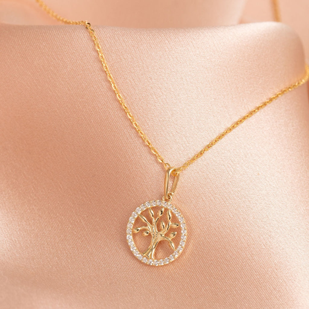 9ct gold tree of life necklace beside a purple ribbon