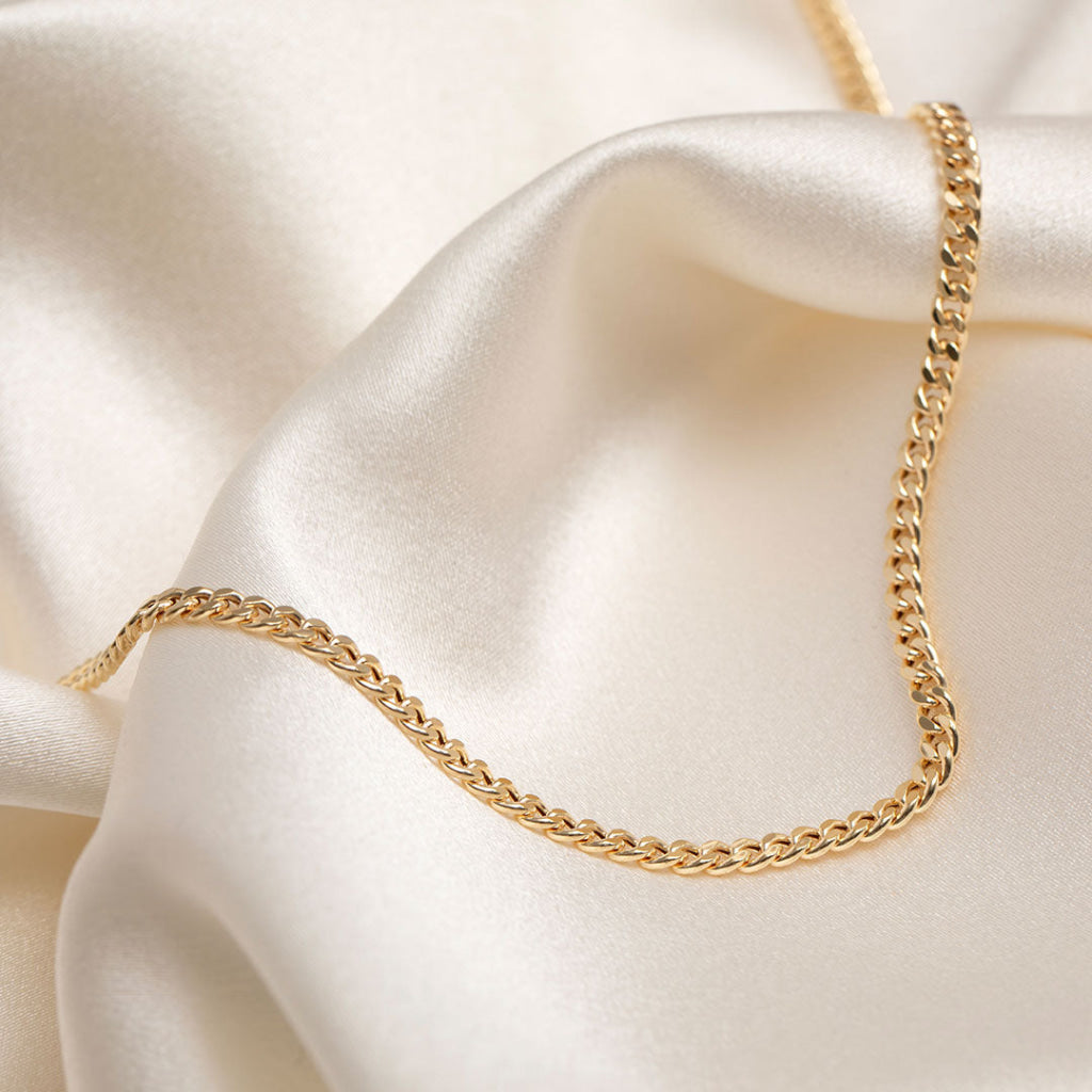 yellow gold curb chain on fabric