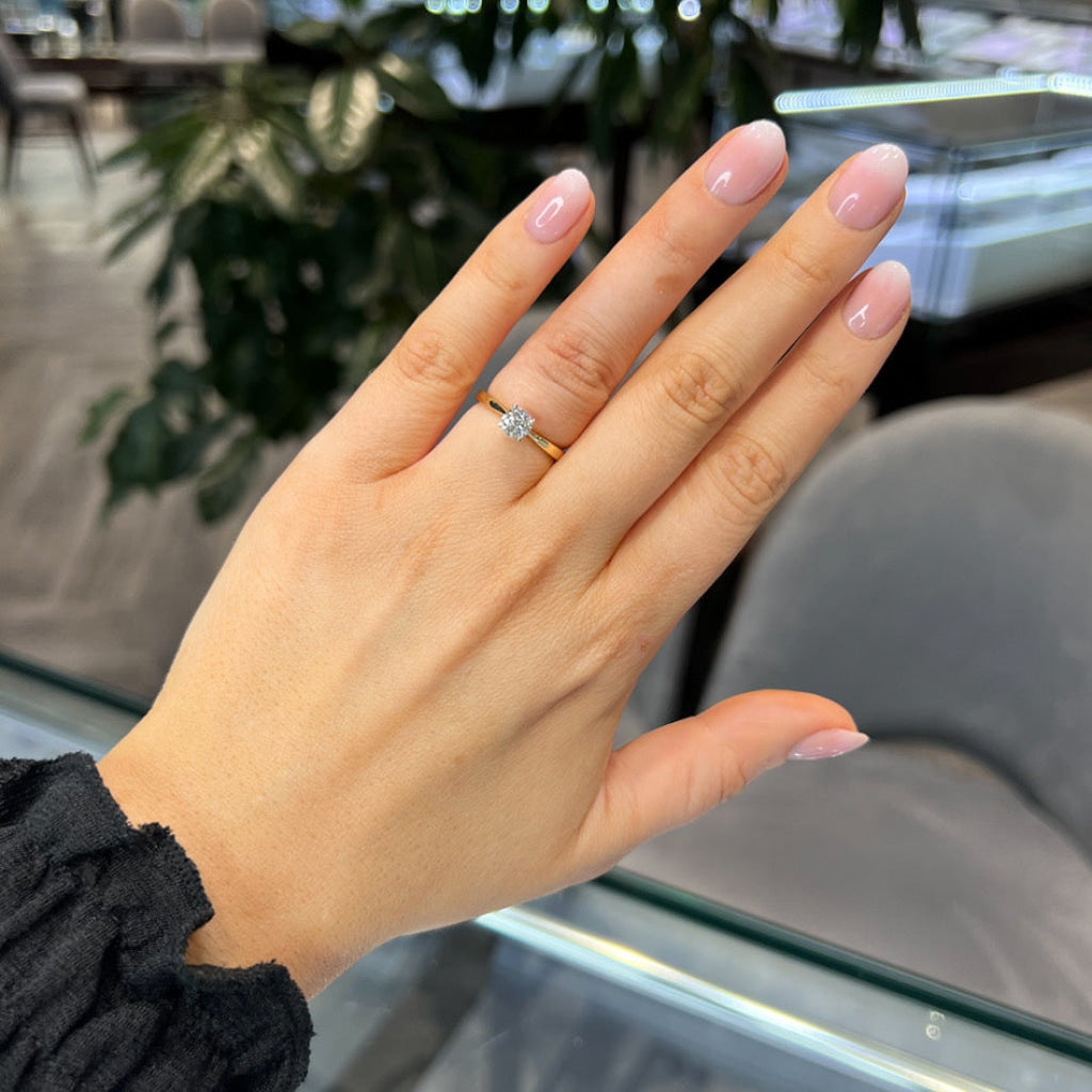 Woman's hand wearing Auric Engagement Ring with gold band.