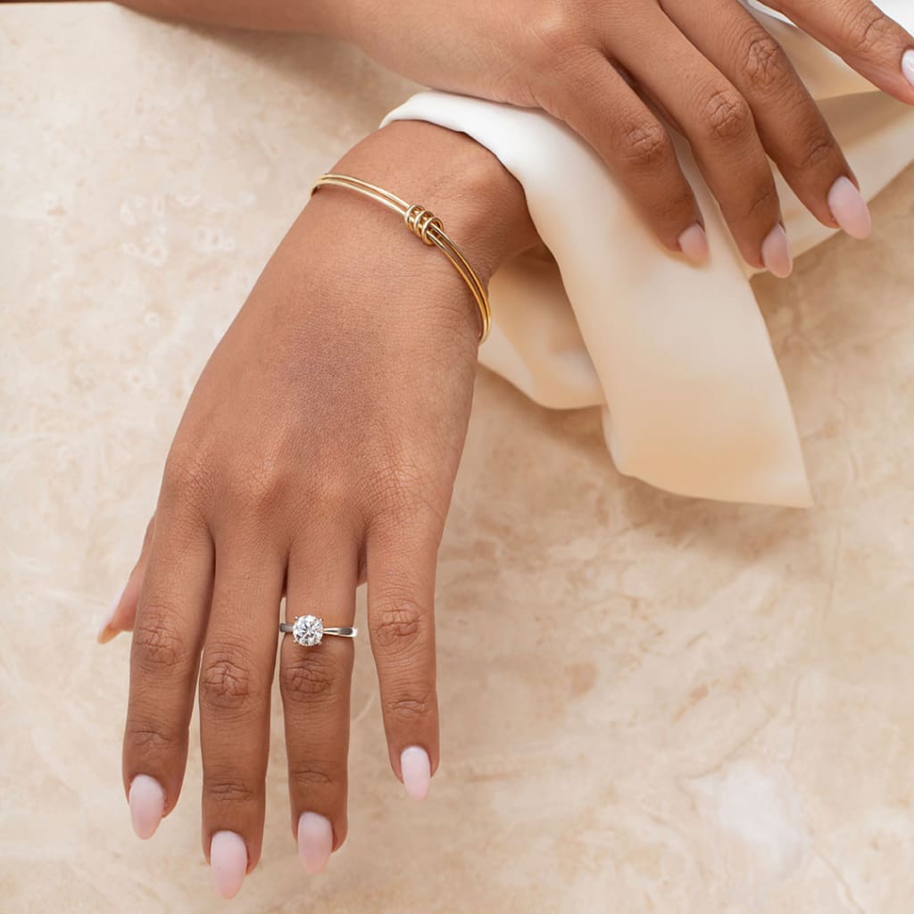 Lady wearing solitaire diamond engagement ring with marble background