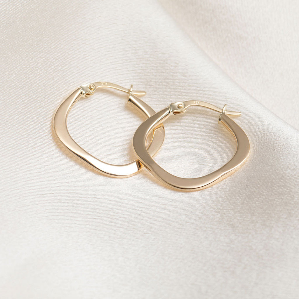 side view of gold paperclip huggie earrings