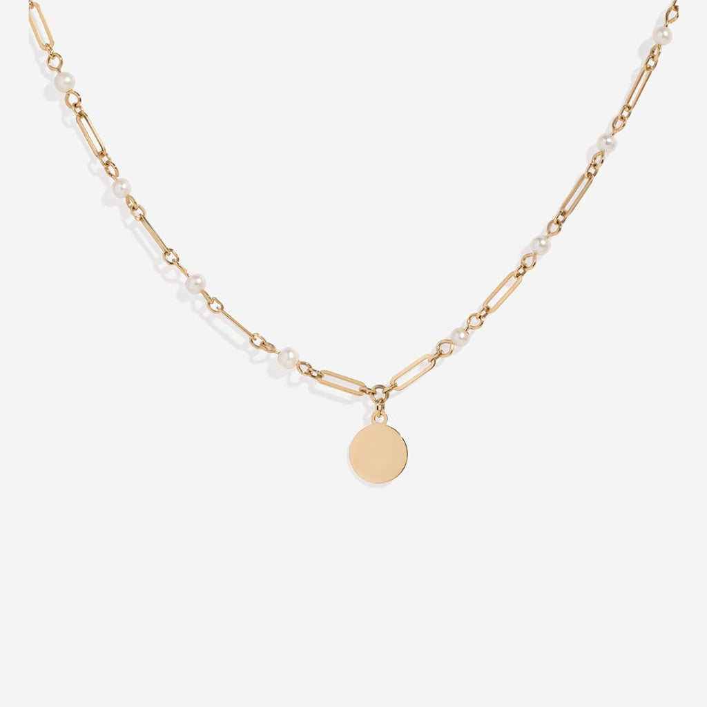 Gold chain necklace with evenly spaced pearls leading to a central disc charm