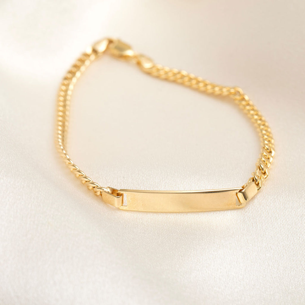 14ct gold id curb bracelet on cream background