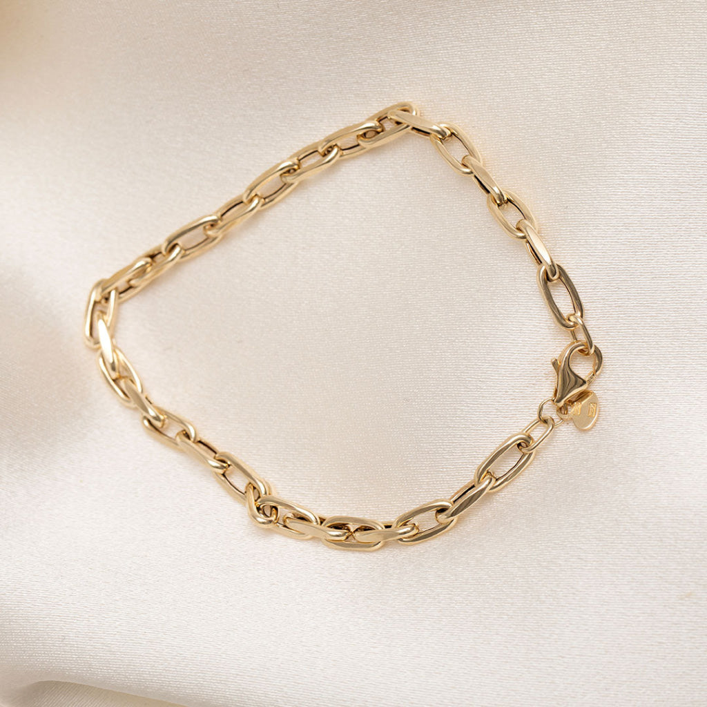 14ct gold oval link bracelet on a cream fabric background