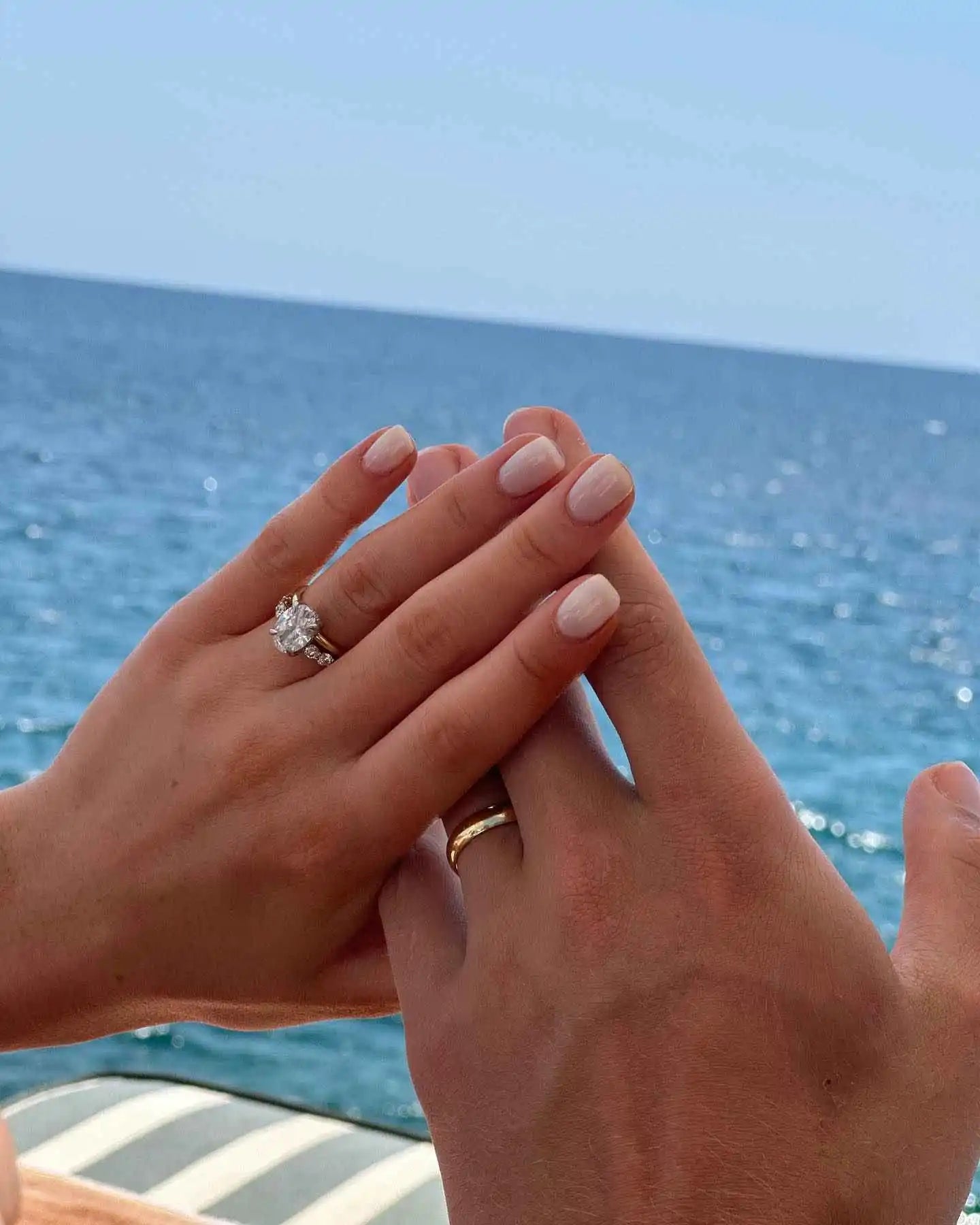 files/diamond-engagement-ring-hand-ocean-backdrop.webp