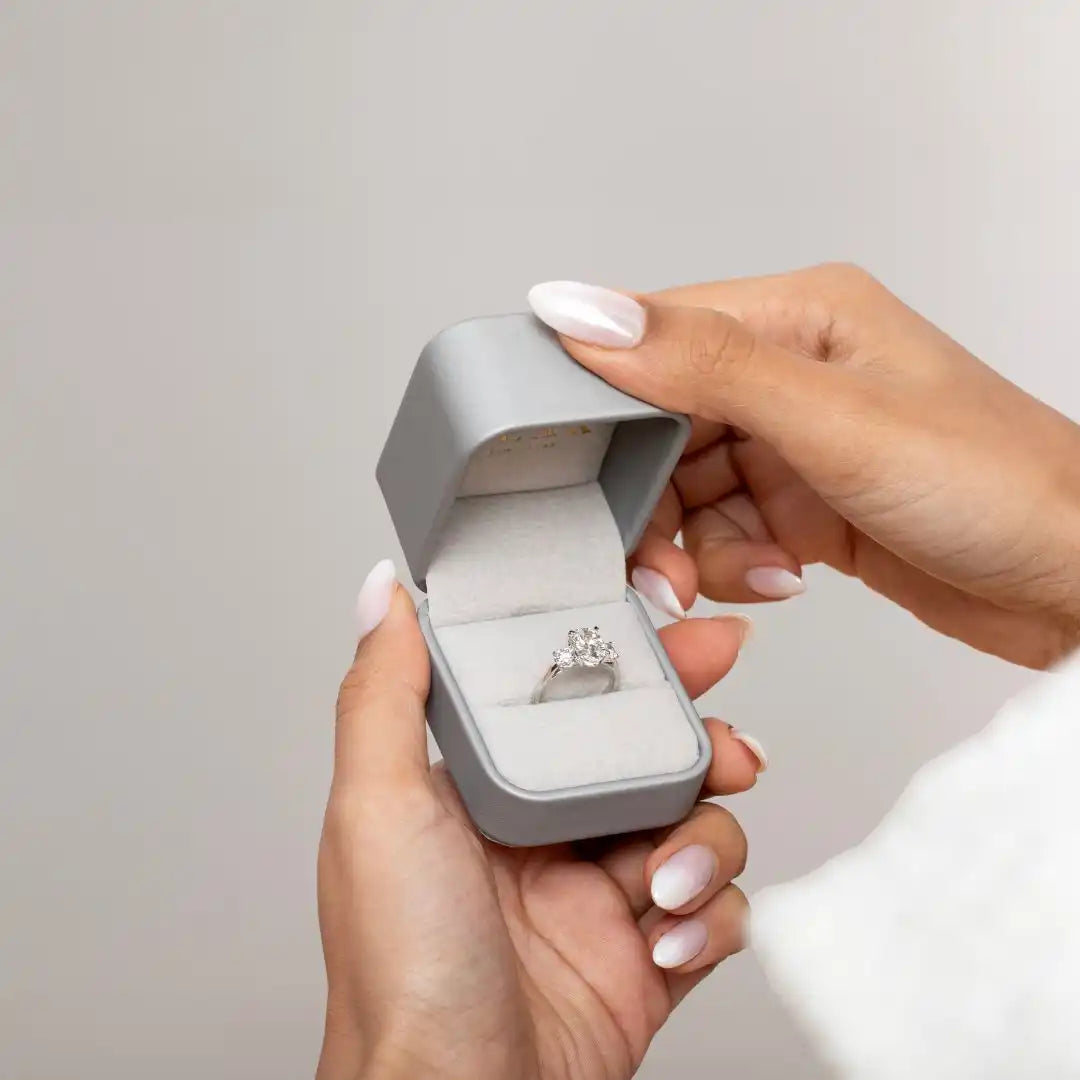 Diamond engagement ring nestled in a light gray ring box.