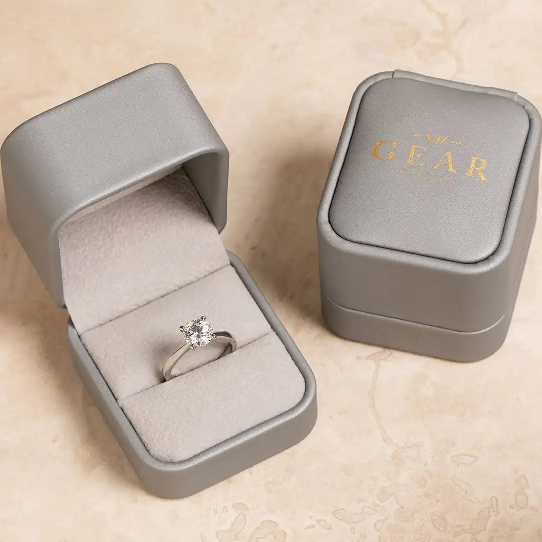 Diamond solitaire engagement ring in a gray velvet ring box.