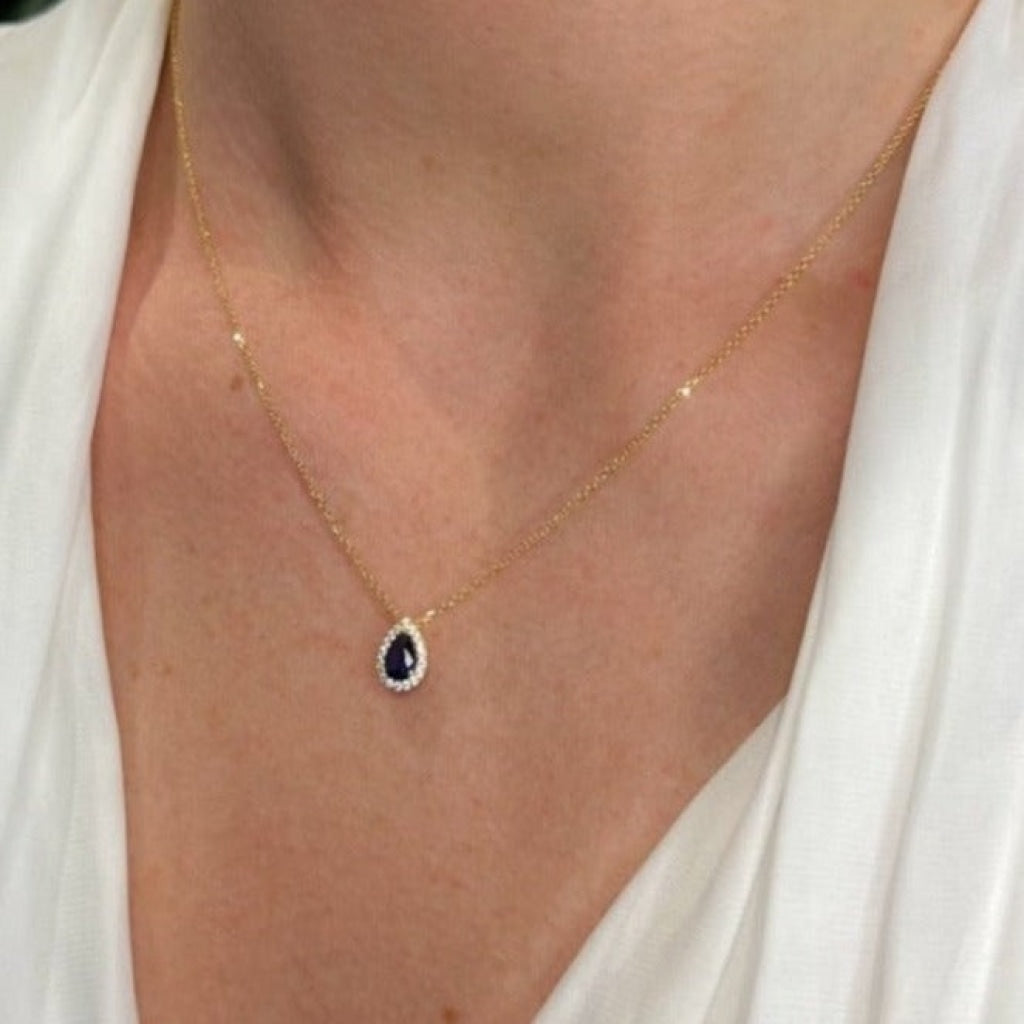gold zirconia necklace with blue stone on ladies neck