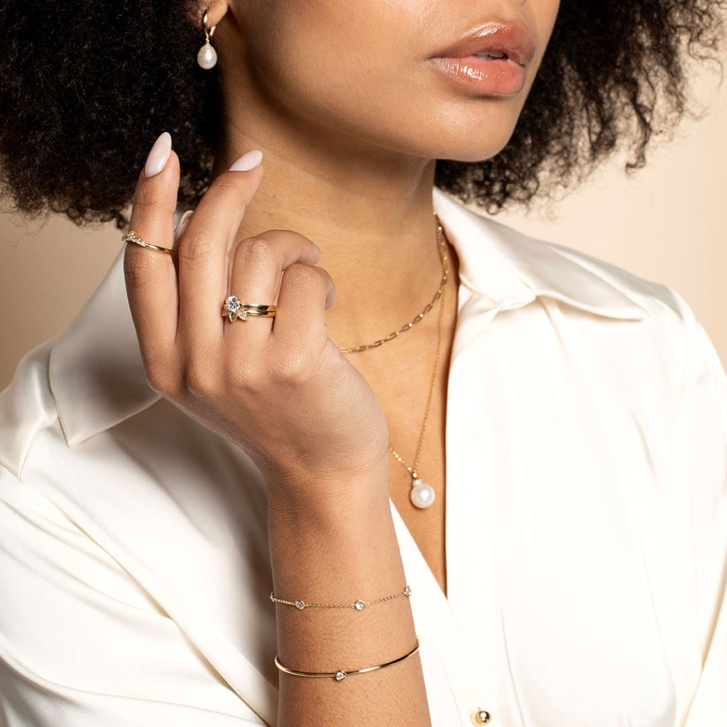 Model wearing set of gold solitaire engagement ring and shaped wedding band