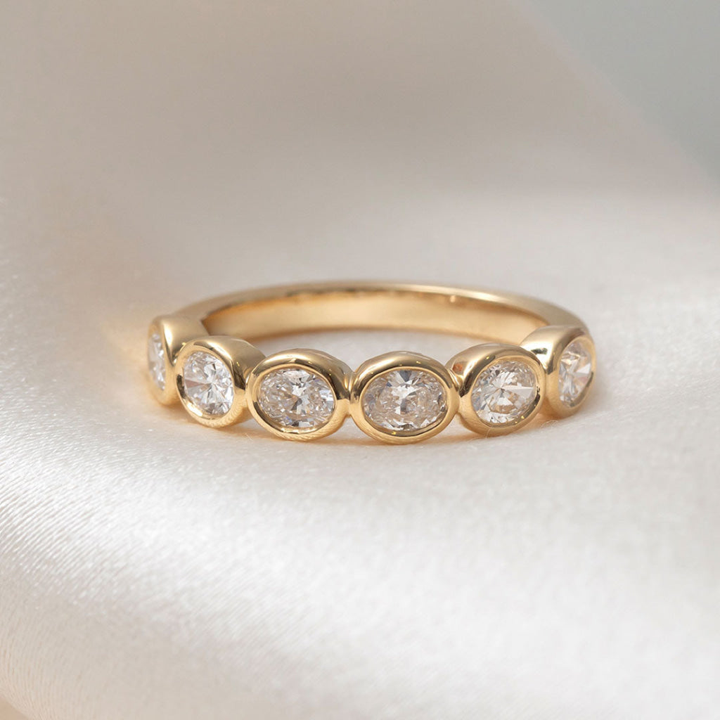 Gold ring with embedded diamonds on a light fabric background
