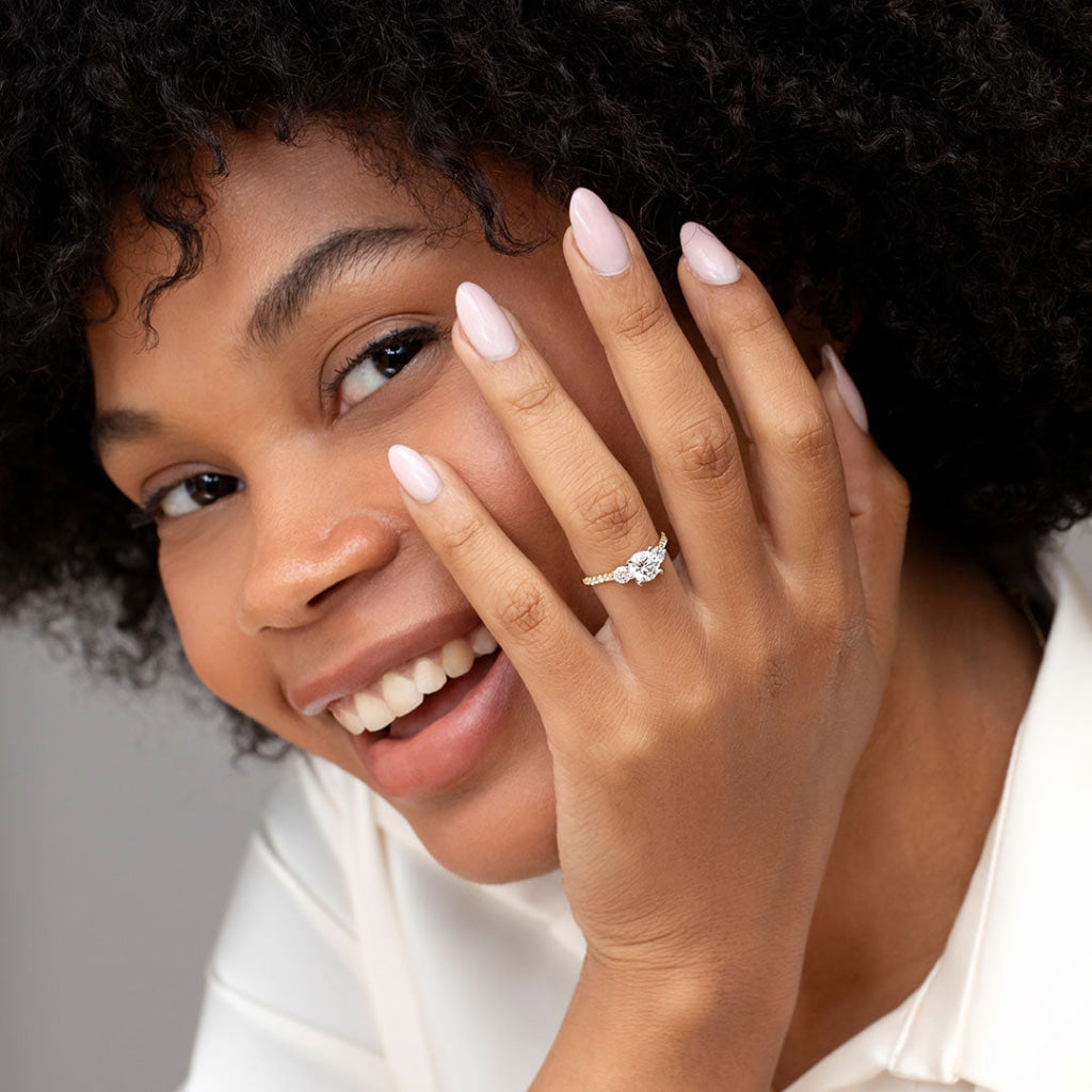 Model smiling wearing three stone diamond engagement ring