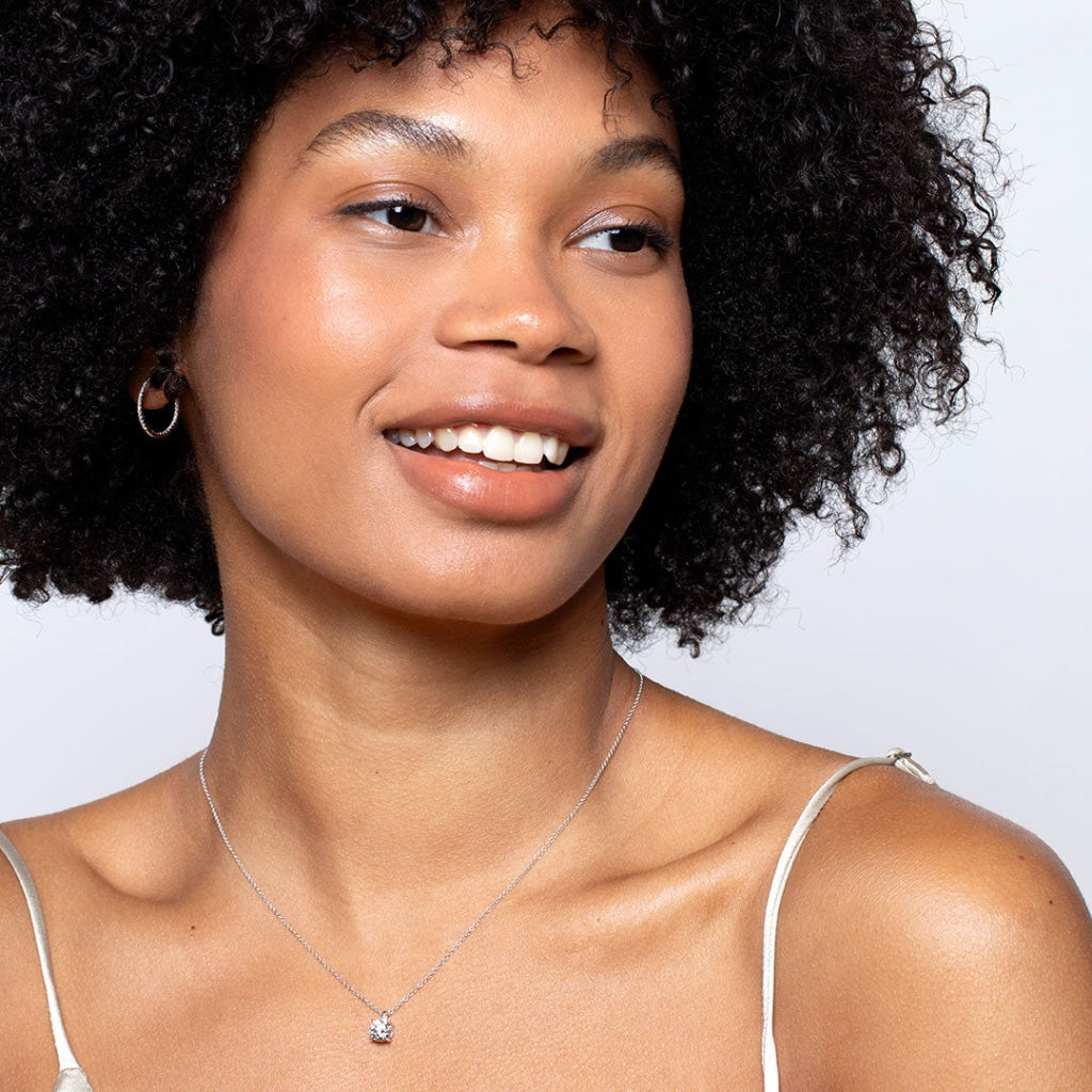 Smiling model wearing solitaire round diamond necklace 