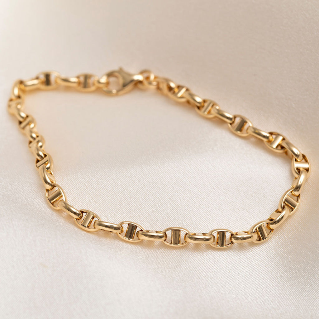 14ct gold fancy chain bracelet on cream fabric background