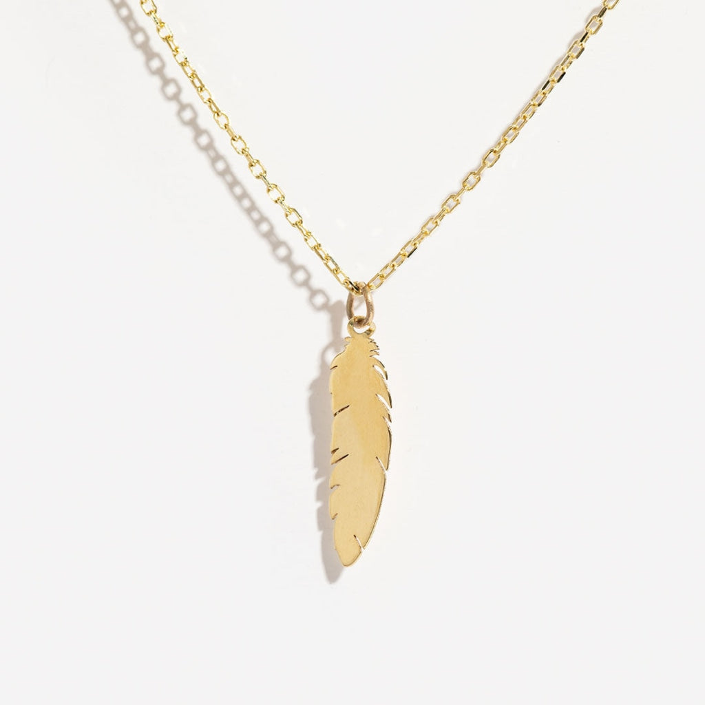 9ct gold feather necklace beside a purple ribbon