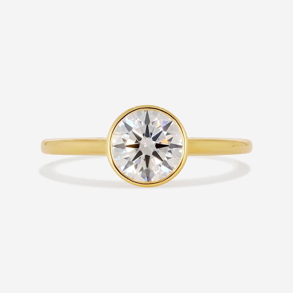 Round cut bezel set engagement ring on white background