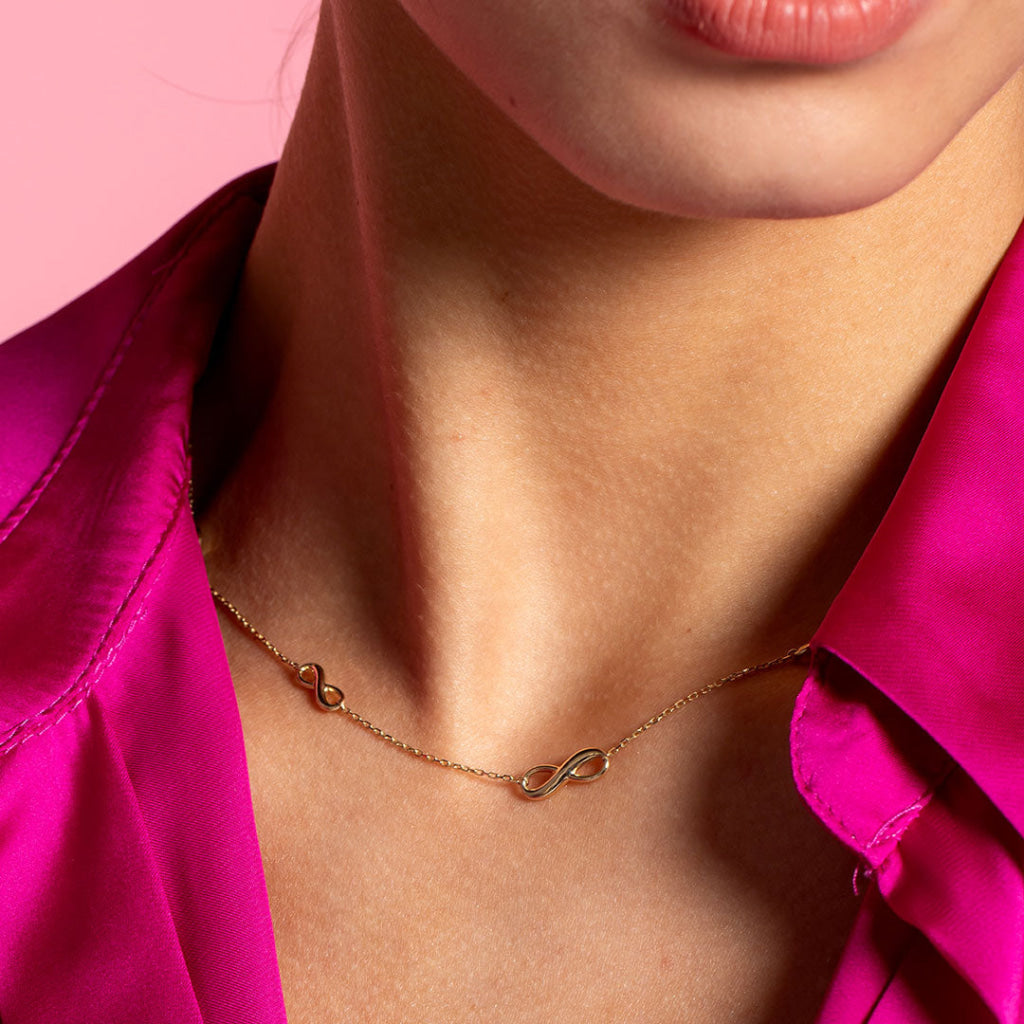 graduated infinity necklace on model wearing pink shirt