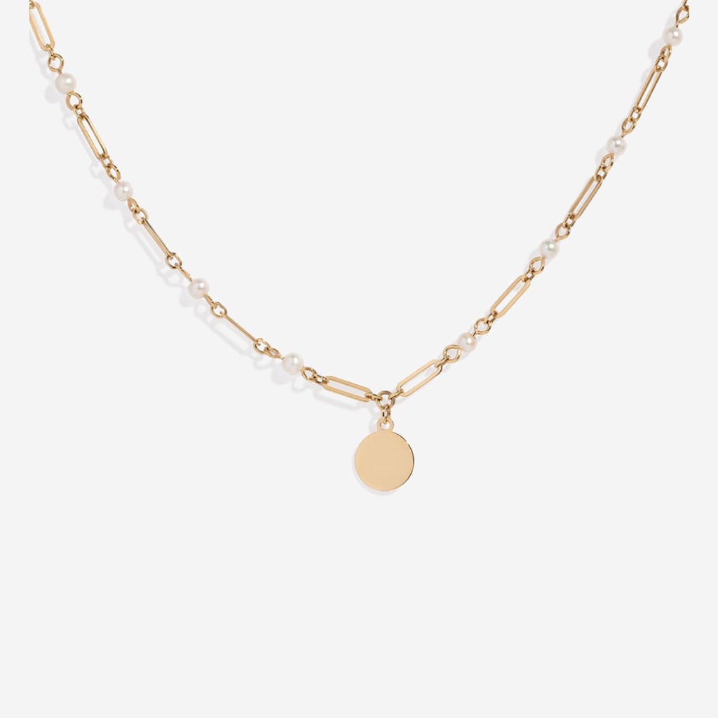 Gold chain necklace with evenly spaced pearls leading to a central disc charm