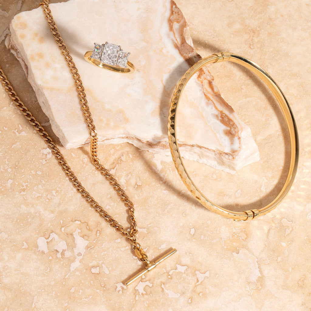 gold t bar paired with bangle and engagement ring