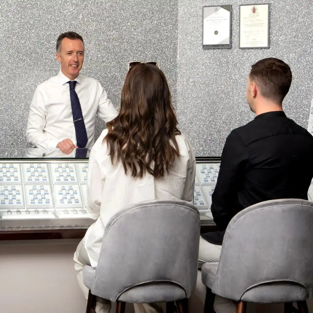 A jewelry store consultation with customers seated at a display counter.