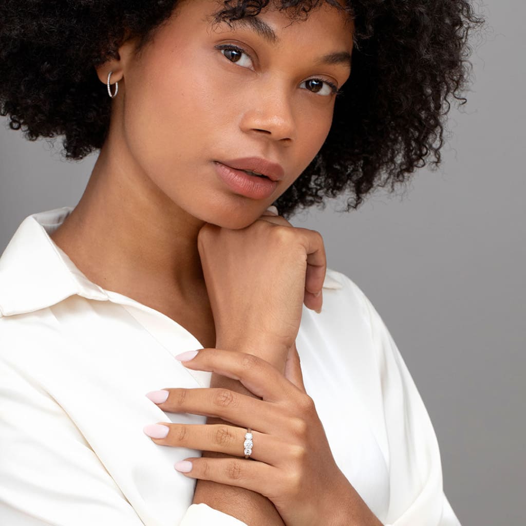 Model holding wrist wearing three stone engagement ring