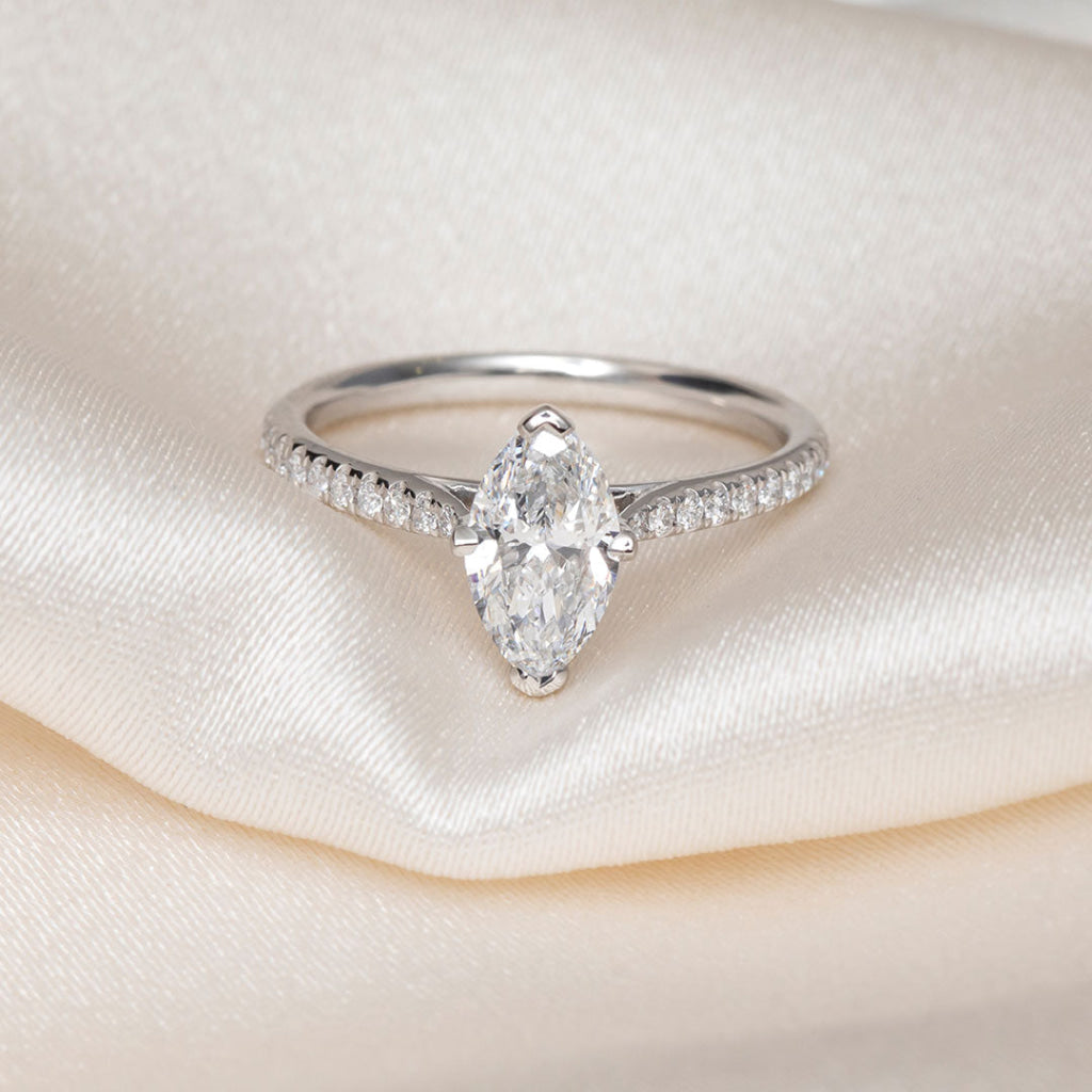 A platinum diamond ring featuring a marquise-cut center stone and pavé-set diamonds along the band.
