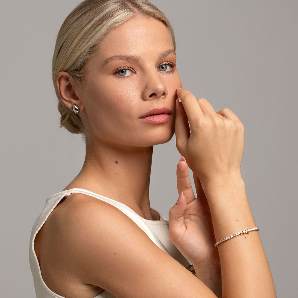 silver earrings paired with diamond tennis bracelet on model