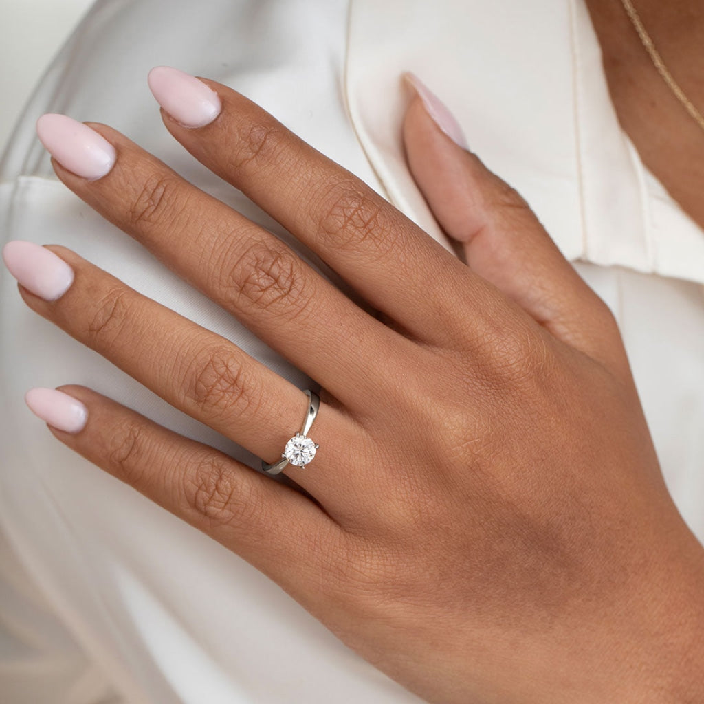 Hand model wearing solitaire platinum diamond engagement ring
