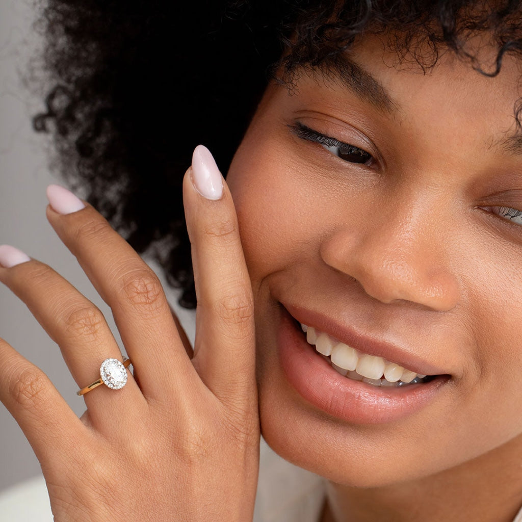 Smiling model wearing oval halo engagement ring