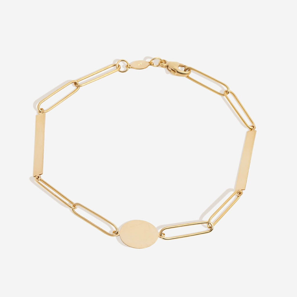 Gold bracelet with disc and bar on white background