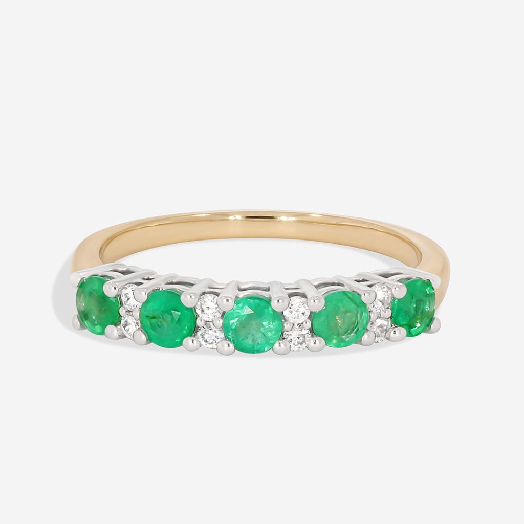 emerald and diamond eternity ring on white background