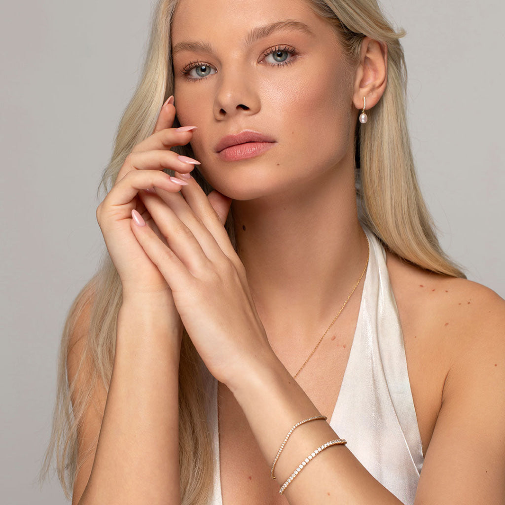 model wearing pearl drop earrings and diamond tennis bracelets