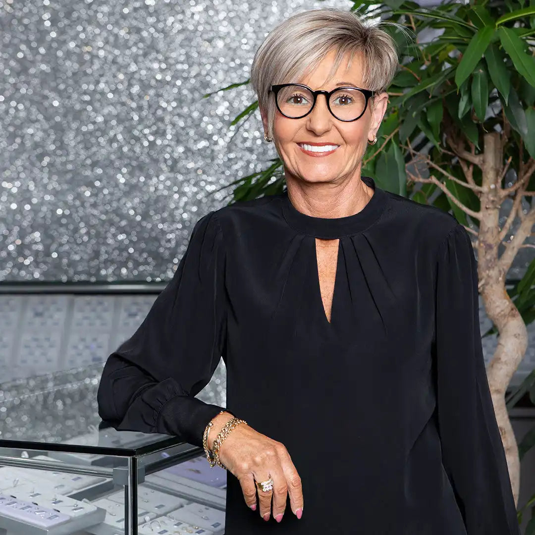 Professional wearing black attire, glasses, and short silver hair.