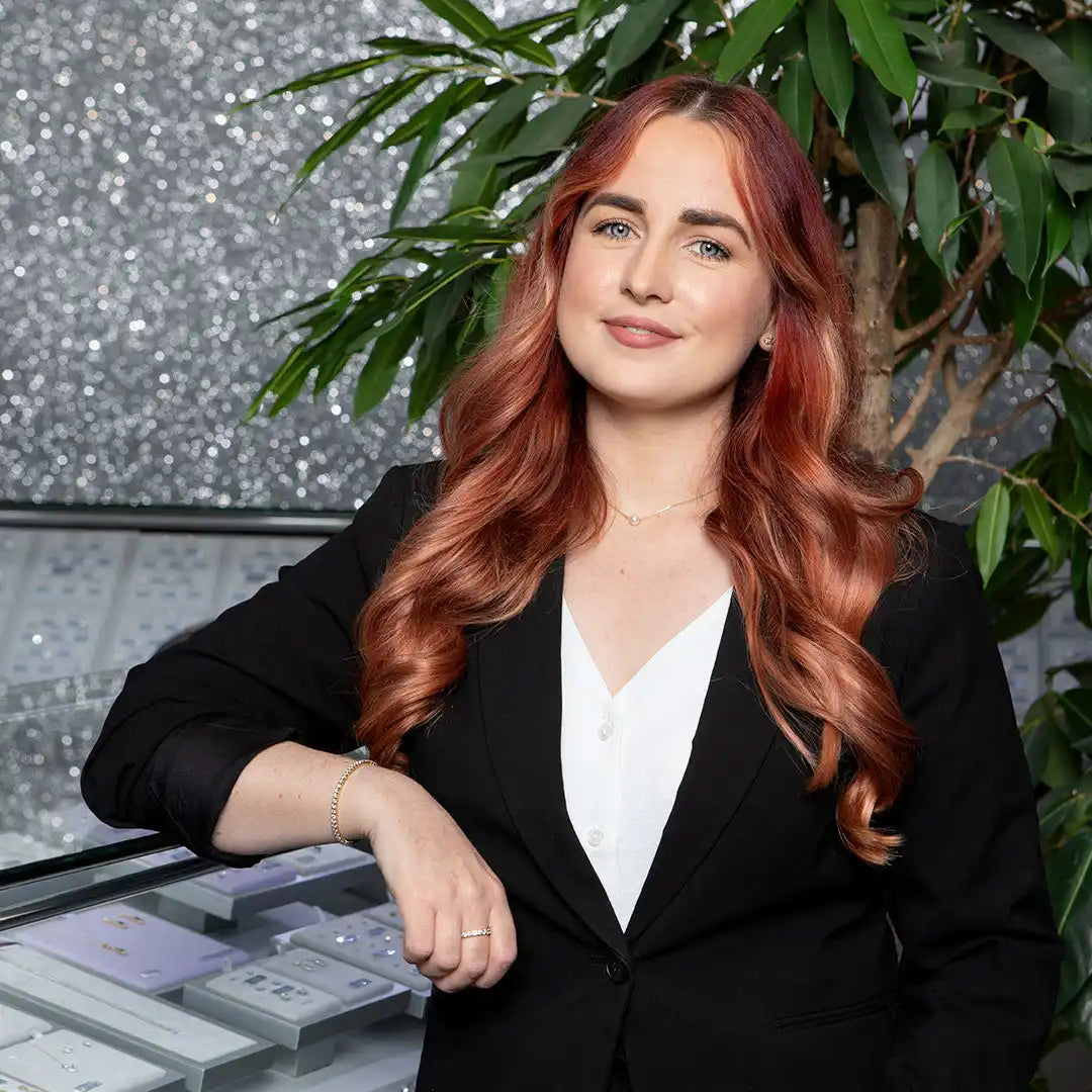 Professional portrait featuring long red wavy hair, a black blazer, and white top.