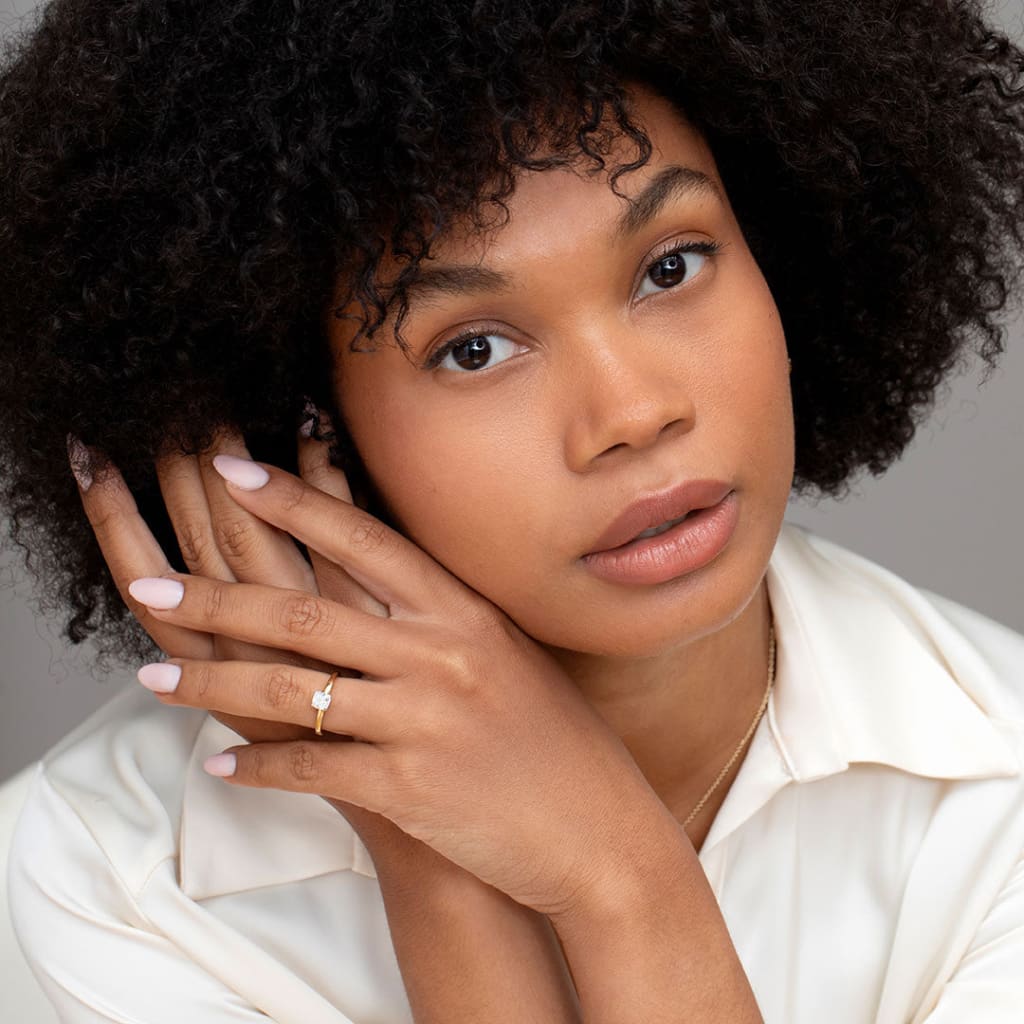 Model touching hair wearing solitaire engagement ring