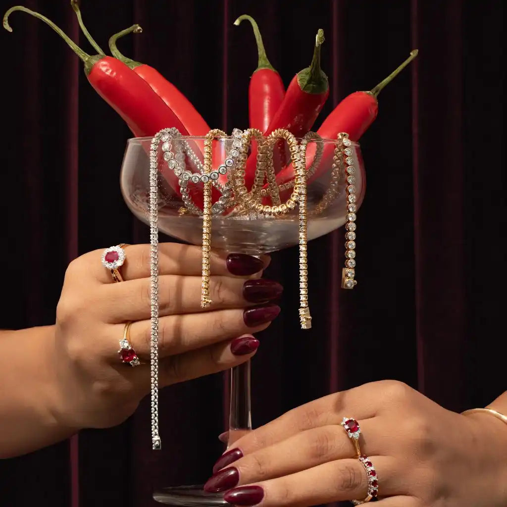 Red chili peppers in a cocktail glass draped with diamond necklaces.