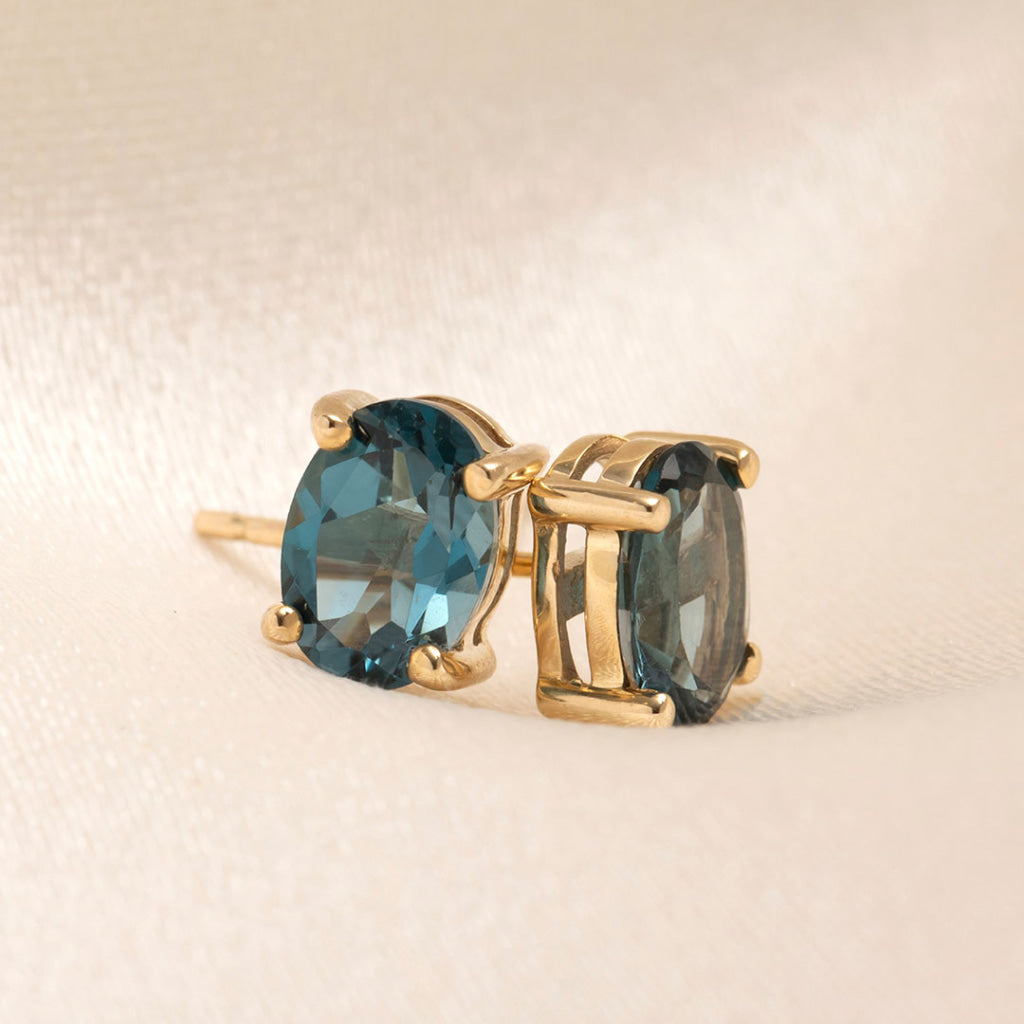 london blue topaz claw set earrings in yellow gold