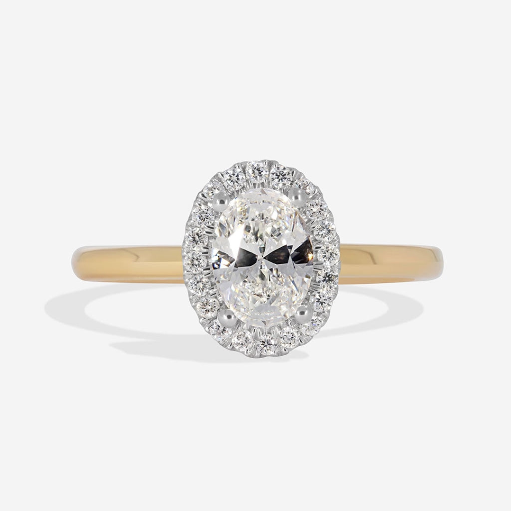 Oval diamond halo engagement ring on a gold plain band.