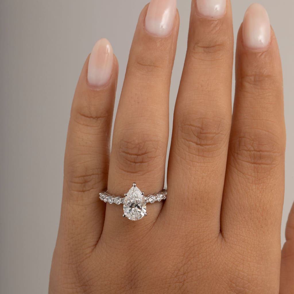 close up of lab grown pear cut engagement ring on finger