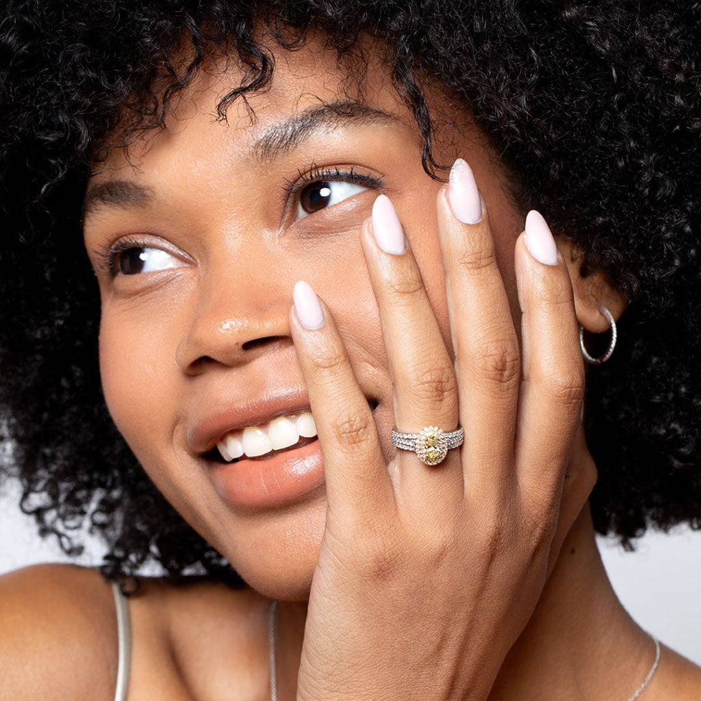 Model with hand on face wearing yellow diamond engagement ring