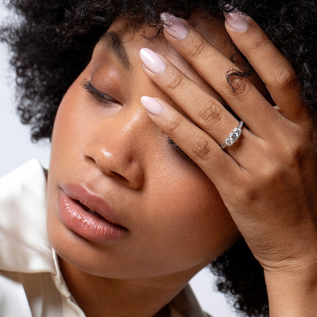 Close up of model wearing three stone diamond engagement ring