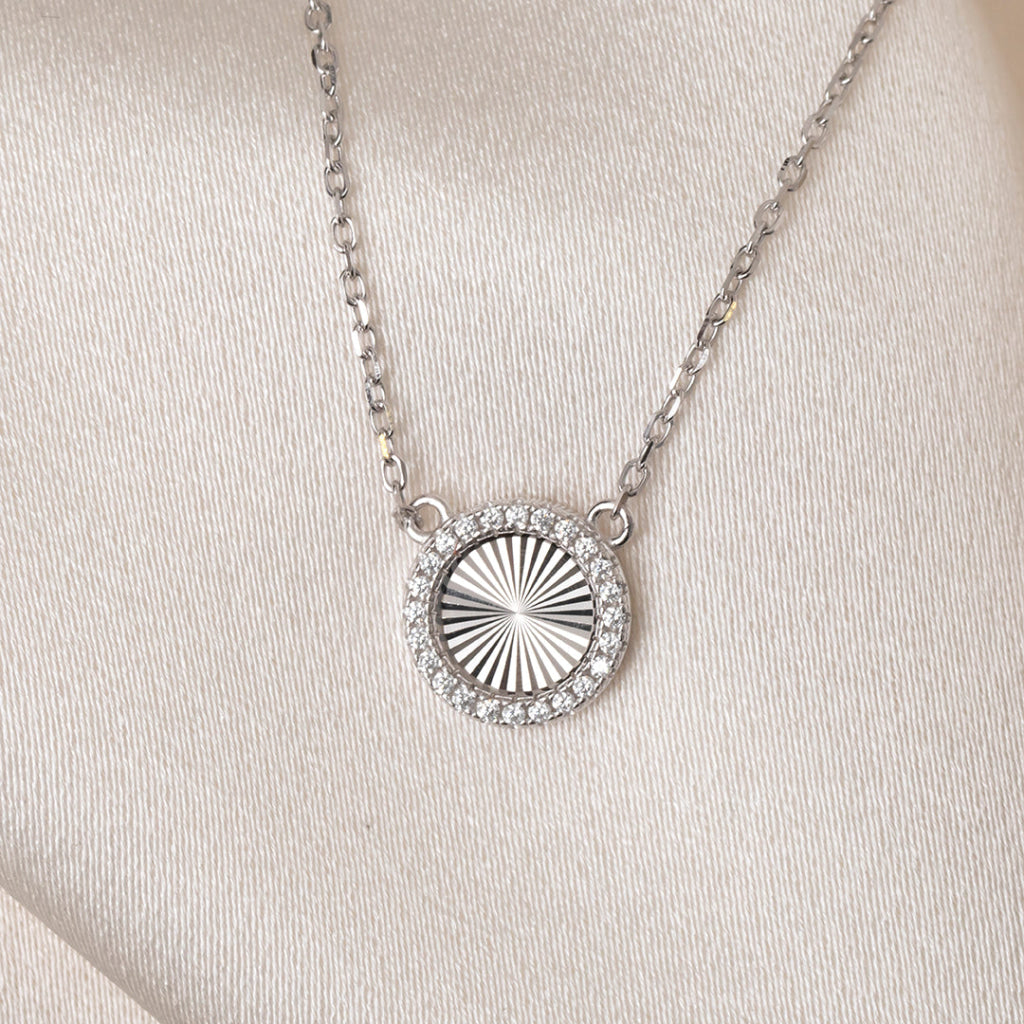 Silver necklace with a circular pendant on a light gray background