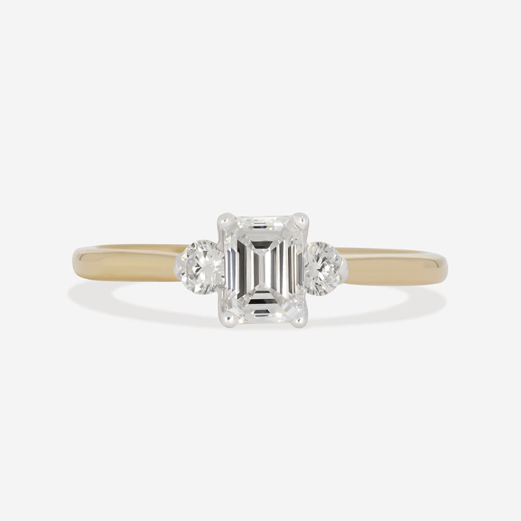 emerald three stone diamond engagement ring on white background