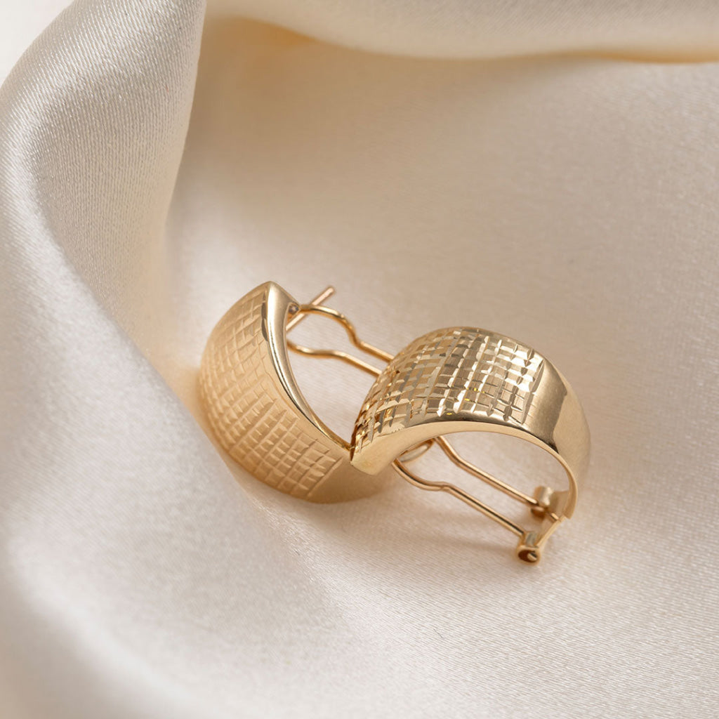 14ct gold half hoop earrings on a cream fabric background