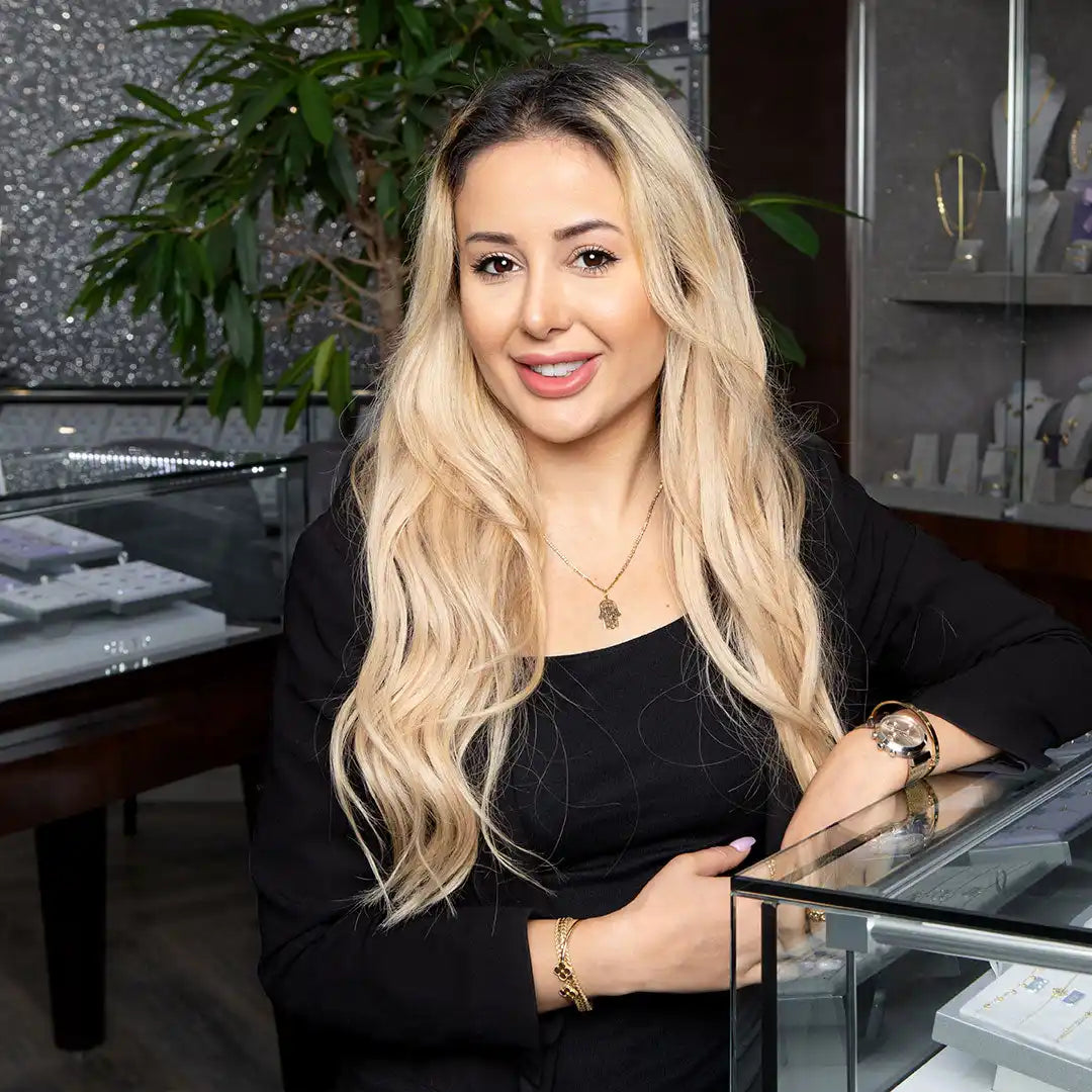 A smiling woman with long blonde hair wearing a black top and jewelry.