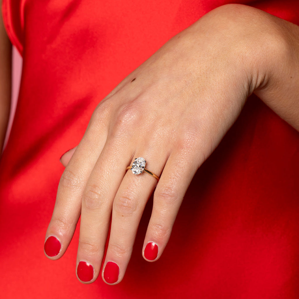 Woman's hand wearing Zariyah Engagement Ring with red dress on
